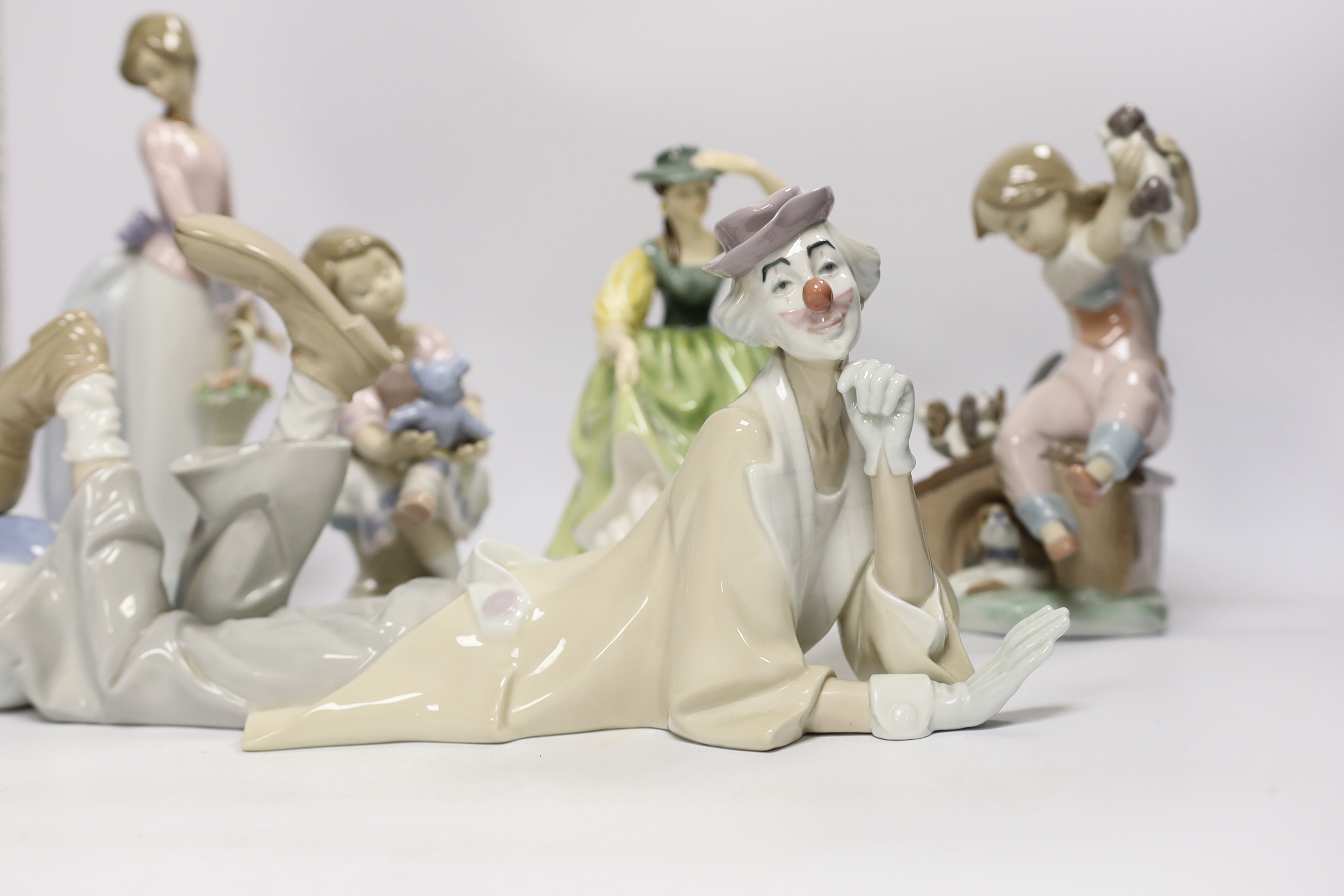 A Lladro recumbent clown, three smaller Lladro figures and a Royal Doulton Buttercup figure, clown 37.7cm wide (5)